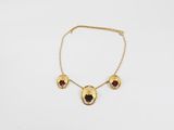 un collier en or orné de grenats sur fond blanc