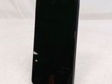 a black cell phone sitting on a stand on a white surface