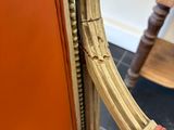 an orange leather chair with a gold frame and wooden legs