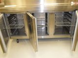 stainless steel counter top with two doors open in a commercial kitchen