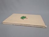 an old book sitting on top of a table with a green frog on it