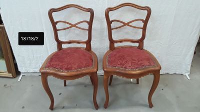 two wooden chairs with red upholstered cushions and a white backdrop