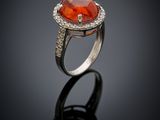 an orange stone and diamond ring on a black surface
