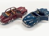 two toy cars sitting next to each other on a white surface