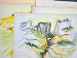 trois aquarelles représentant des montagnes et des arbres, posées sur une table