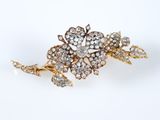 un gros plan sur une broche en forme de fleur en or et diamants