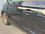 a black car parked in front of a blue garage