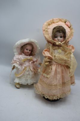 Deux poupées en porcelaine, représentant une femme et un enfant, sont placées l'une à côté de l'autre