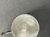 a close up of a silver plate with a handle on a table