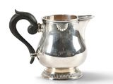 silver plated pitcher with black handle and curved handle on a white background