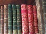 several old books are lined up in a row on a shelf