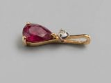 un gros plan sur une broche en pierre rouge et diamants