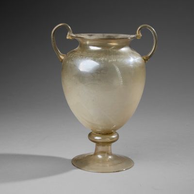 un vase en verre posé sur un socle, sur une surface grise