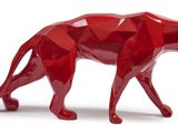 the red sculpture of a cheetah is standing on a white surface