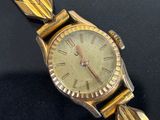 an image of a gold wrist watch with roman numerals on a black surface