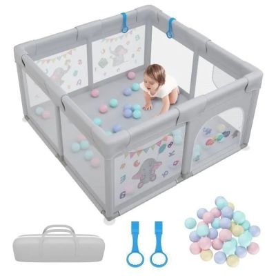 Le bébé joue dans son parc avec des balles et une paire de ciseaux.