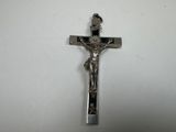 silver crucifix on a white table with a white background