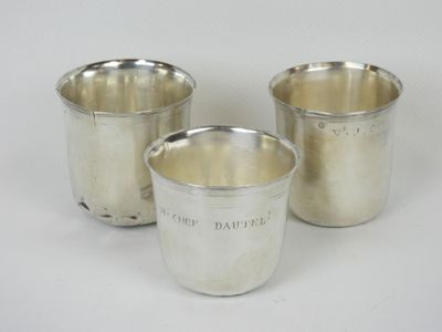 trois tasses en argent posées l'une à côté de l'autre sur une surface blanche