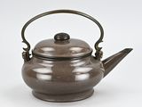 a brown teapot with a handle on a white surface