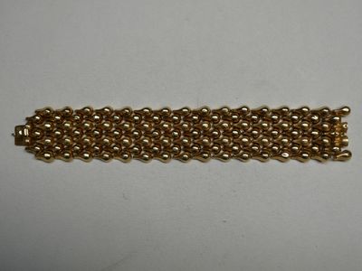 gros plan d'un bracelet en chaîne en or sur une surface blanche