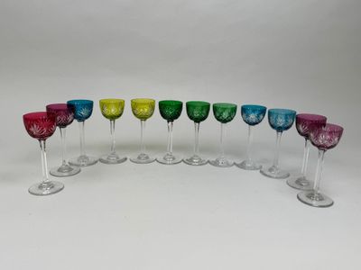 six verres à vin colorés alignés sur une surface blanche