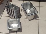 quatre casseroles remplies de nourriture sont posées sur le carrelage d'une cuisine