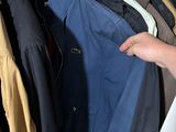 a person that is holding some clothes in a closet