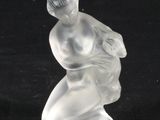 une figurine en verre représentant un homme à genoux sur une surface noire