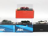 Quatre modèles réduits de voitures différents sont exposés dans une vitrine posée sur une surface blanche.