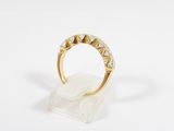 a gold and diamond ring on a clear acrylic stand