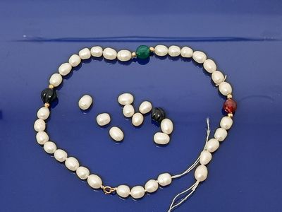 une photo d'un ensemble composé d'un collier et de boucles d'oreilles, posée sur un fond bleu