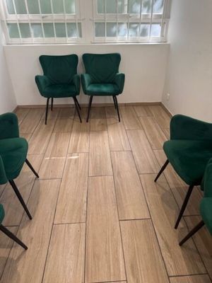 Plusieurs chaises vertes sont disposées en cercle dans une pièce.
