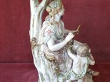 une figurine représentant une femme et deux enfants assis sur un arbre