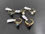 six different types of pearl rings on a black surface