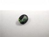 a green tourmaline gems on a white surface