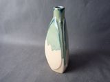 a green and white vase sitting on a gray surface