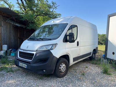 La camionnette blanche est garée à côté d'une remorque dans la cour.