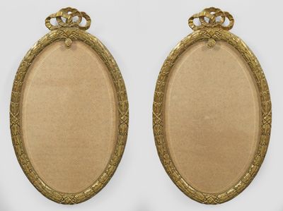 two gold oval frames with ornate designs on them against a white background