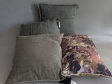 three pillows on a white surface with a tag attached to them