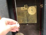 a hand that is holding a clock in front of a wall