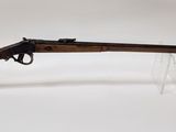 a rifle with a wooden barrel and clear acrylic display stand