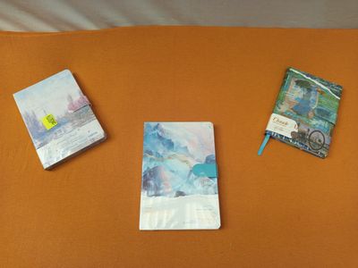 trois livres posés sur un lit recouvert de draps orange