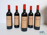four bottles of red wine are lined up on a table