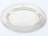 une assiette ovale en argent, avec un bord en argent sur une surface blanche