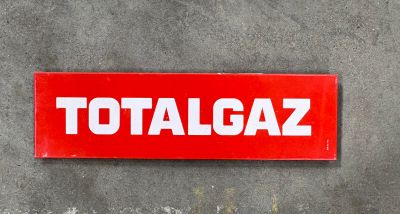 une enseigne rouge portant l'inscription « totalgaz » sur le mur d'un immeuble