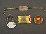three pieces of jewelry including a keychain, a coin, and a medal