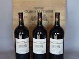three bottles of red wine sit in front of a wooden box