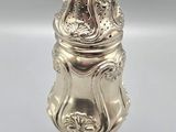 an antique silverplated salt shaker on a pedestal