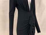 La robe est noire, elle a des manches longues et un col en V.