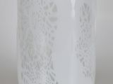 un gros plan d'un vase en verre orné d'un motif blanc